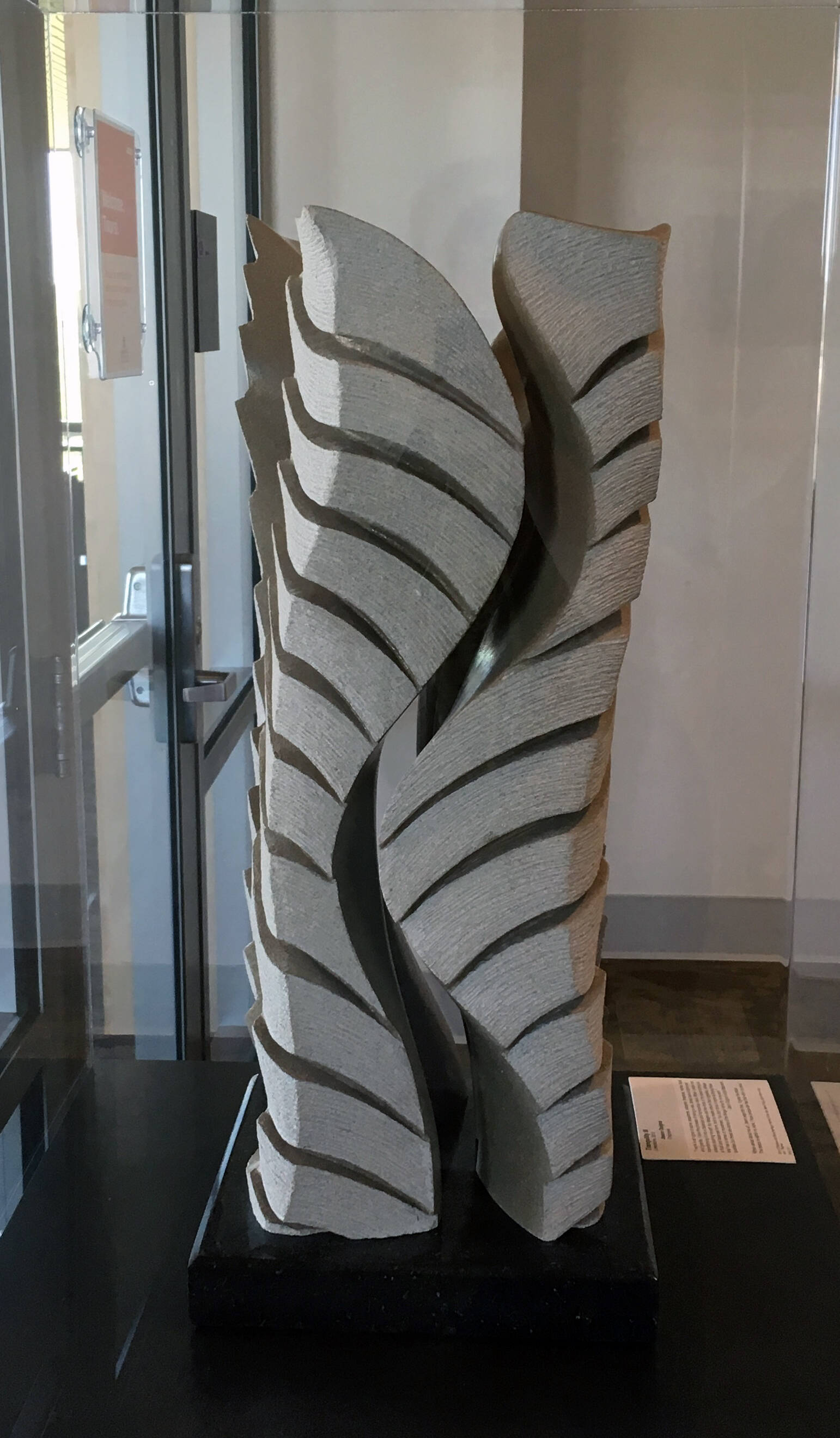 Tall limestone sculpturein two pieces that connect through a pattern of curves.